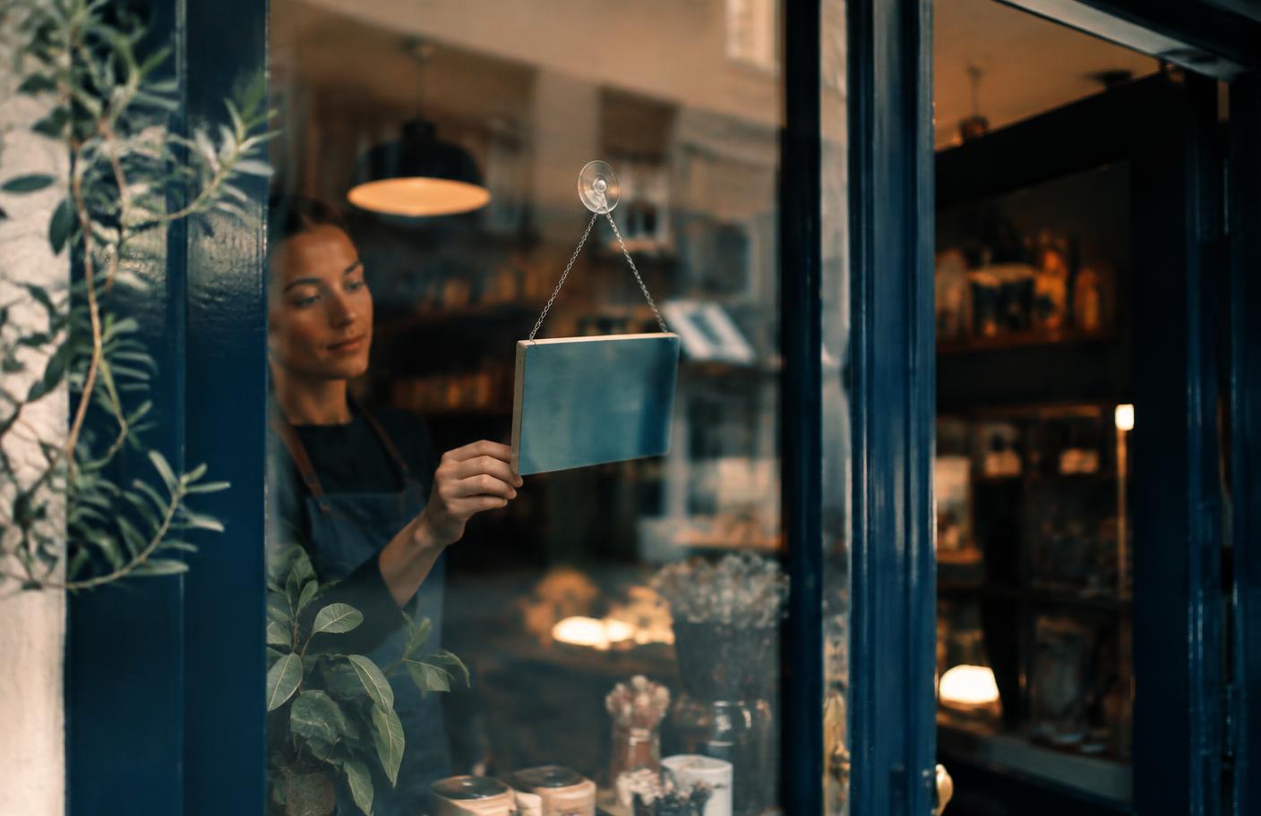 A shop owner hanging a sign in a storefront window